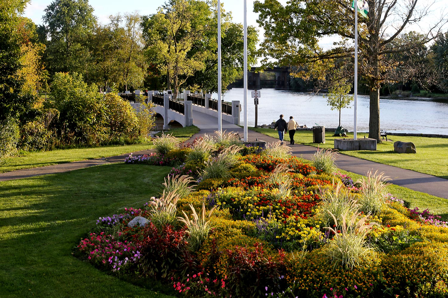 Landscaped gardens and an arched bridge along the Fox River in Geneva