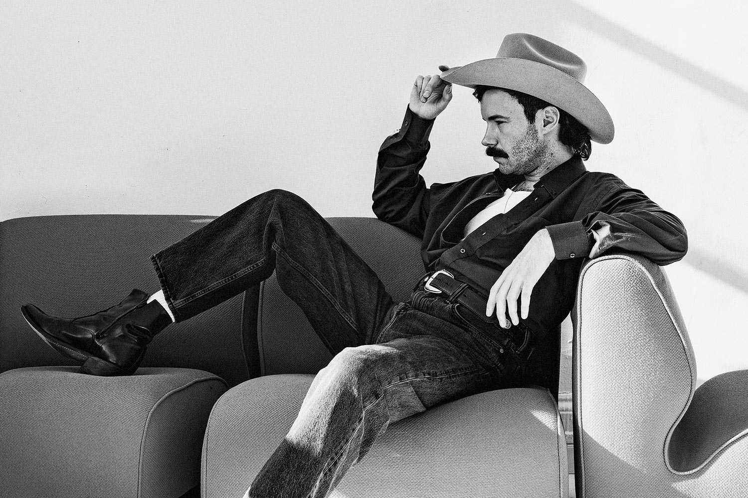 Andrew Sa wearing a cowboy hat, posing on a couch