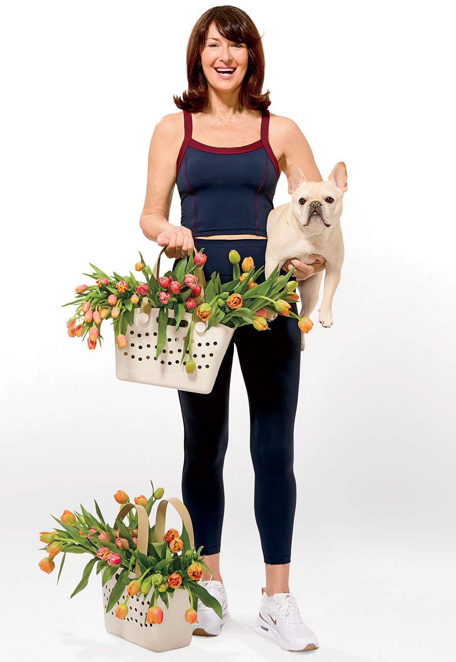 Debi Lilly carrying a basket of flowers and her dog