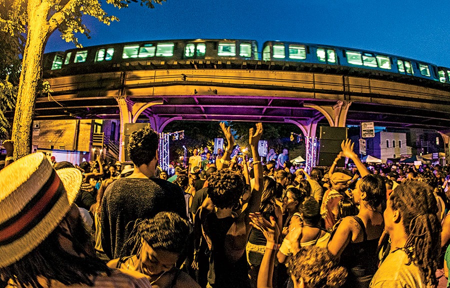 Sound System Block Party, shown here in 2014, with a crowd of people under the L tracks on Milwaukee Avenue.